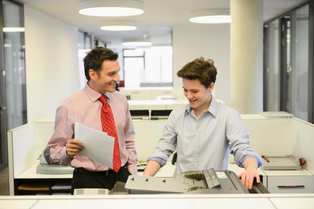 ترجمة معتمدة للهيئة العامة للاستثمار والمناطق الحرة - Two employees copying documents and chatting